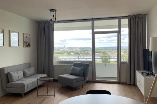 a living room with a couch and chair and a large window at Rheinblick - Wohnung direkt bei Düsseldorf mit toller Aussicht in Neuss