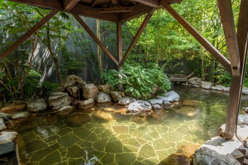a pond in a garden with a gazebo at Setsugetsuka in Hakone
