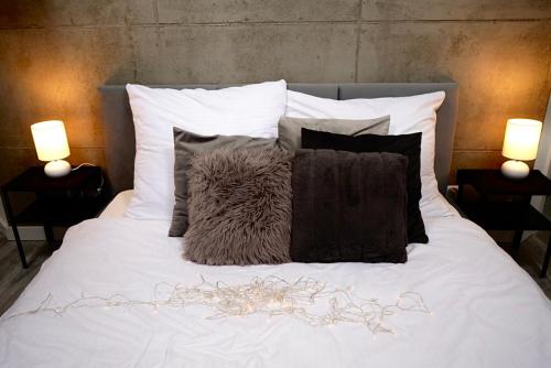 a bed with black and white pillows and two lamps at Bunkier House in Niedźwiada
