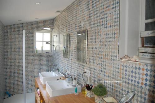 La salle de bains est pourvue de 2 lavabos et d'un mur en briques. dans l'établissement La Maison d'Été, à Noirmoutier-en-l'lle