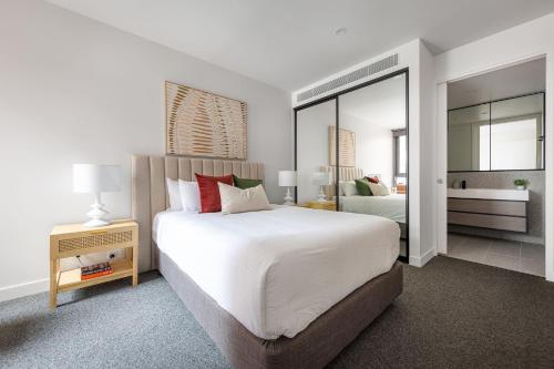a bedroom with a large bed and a mirror at Richmond Apartments with Urban Rest in Melbourne