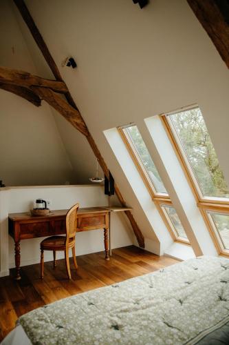 an attic room with a desk and windows at Les Bucoliques de la Noë in Goven