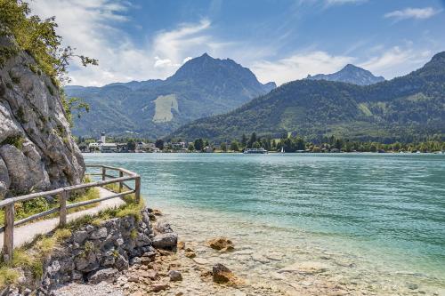 a bench next to a body of water with mountains at SeenSucht in Strobl