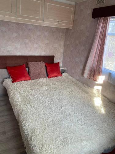 a bed with two red pillows in a bedroom at Przyczepa holenderska in Ińsko