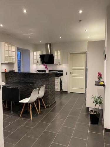 a kitchen with a counter and two chairs and a table at Ferielejlighed i landlige omgivelser in Vejle