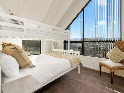 Un dormitorio con una cama blanca y una ventana grande. en Lindmore Retreat & Spa - Luxury Family Home - Queenstown, en Queenstown