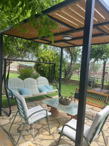 a patio with chairs and a table under a pergola at Mama’s Sunshine Garden Villa in Áyios Ilías