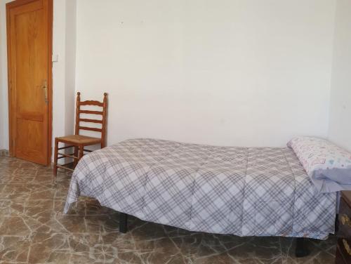 a bedroom with a bed and a wooden door and a chair at Vacansis Habitaciones Privada en una Villa a un paso del Mar en Cullera in Cullera