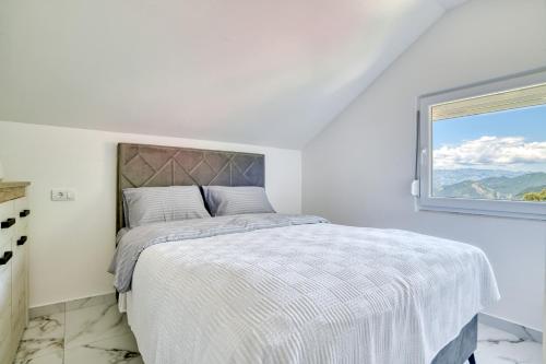 ein weißes Schlafzimmer mit einem Bett und einem Fenster in der Unterkunft Apartment Paradise in Kotor