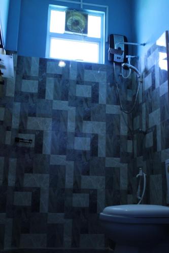 a bathroom with a toilet and a window at Raj Mahal Inn in Wadduwa