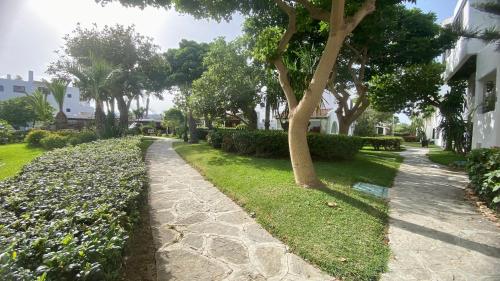 a walkway through a yard with trees and grass at kabila - Villa de Luxe Pied Dans L'eau in Tetouan