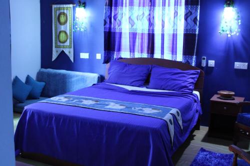 a blue bedroom with a bed and a couch at Raj Mahal Inn in Wadduwa