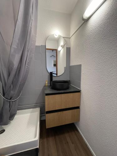 une salle de bain avec un lavabo noir et un miroir dans l'établissement Parenthèse au bord de l'eau, à Port-la-Nouvelle