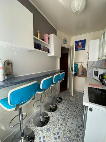 une cuisine avec tabourets de bar bleus à un comptoir dans l'établissement Near Paris, charming quiet sunny 2 rooms, à Pantin