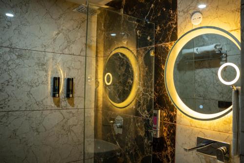 a bathroom with a shower with a round mirror at Hotel W Grand - A Boutique Hotel in Haridwār