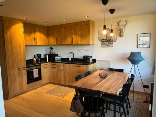 une cuisine avec une table en bois et quelques chaises dans l'établissement Appartement rez de jardin Megeve, à Megève