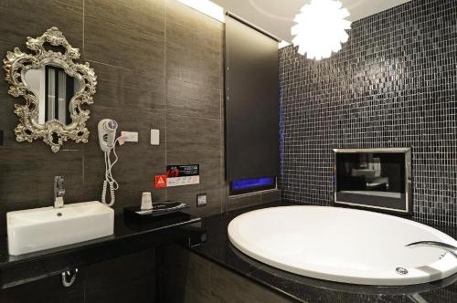 a bathroom with a tub and a sink and a mirror at M Hotel in Caotun