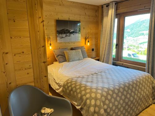 une chambre avec un lit, une chaise et une fenêtre dans l'établissement Appartement rez de jardin Megeve, à Megève