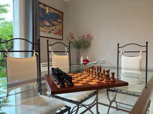 un échiquier sur une table en verre dans une pièce dans l'établissement Belle maison familiale - Proche Golf National, à Montigny-le-Bretonneux