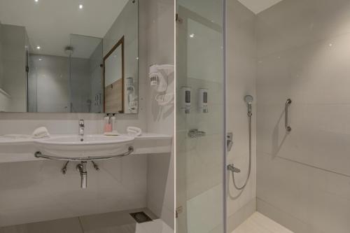 a white bathroom with a sink and a shower at Iris Park Hotel New Delhi in New Delhi