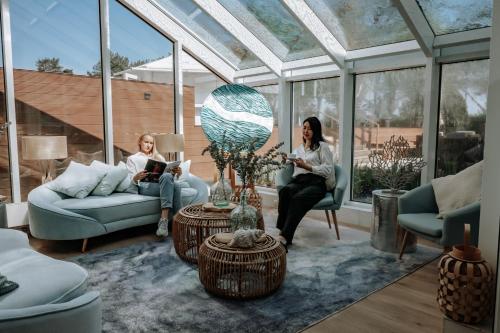 two women sitting in a living room with windows at Arkona Strandhotel in Binz
