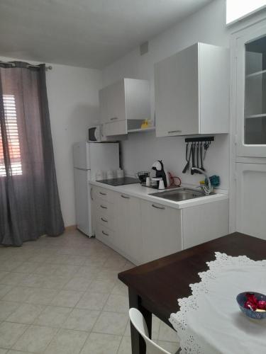 eine weiße Küche mit einem Waschbecken und einem Tisch in der Unterkunft A casa di Mimma in Palazzo Adriano