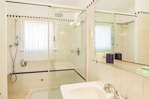 a white bathroom with a shower and a sink at Tenuta Bussadori - Casa Del Timoniere in Poggio