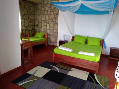 Un dormitorio con una cama verde y una silla. en Chambre d'hôte Ristorante Pizzeria Liberta, en Ranohira