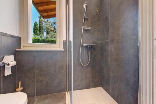 a bathroom with a shower with a toilet and a window at Villa con vista mozzafiato sul Lago in Bardolino