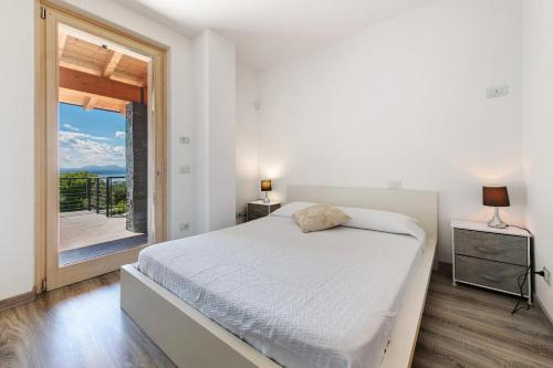 a white bedroom with a bed and a large window at Villa con vista mozzafiato sul Lago in Bardolino