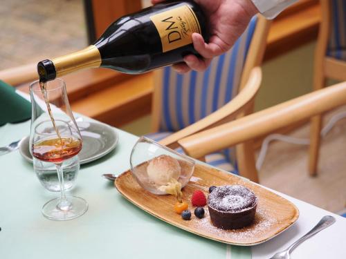a person pouring a bottle of wine into a dessert at Forsthaus Langenberg in Bansin