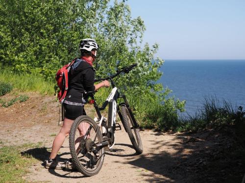 a person with a bike on a path near the water at Forsthaus Langenberg in Bansin