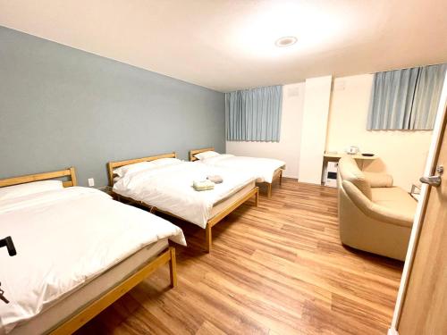 a hotel room with two beds and a chair at Little Garden in Otaru