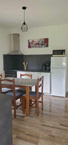 une cuisine avec une table et des chaises et un réfrigérateur blanc dans l'établissement au Bonhomme de Chemin, à Saint-Martin-de-Ribérac