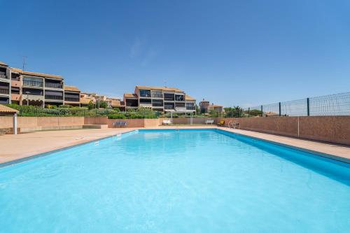 une grande piscine bleue avec des bâtiments en arrière-plan dans l'établissement Les Eaux Vives 1, à Fleury