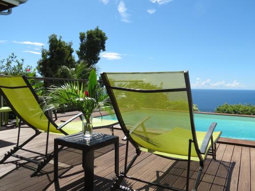 a deck with chairs and a table and a pool at Domaine Racines e Zel - Gîte PomKajou in Vieux-Fort