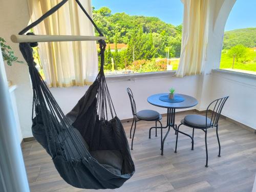 a hammock in a room with a table and chairs at House Kapetanović in Rab