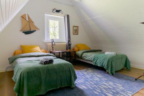 - une chambre mansardée avec 2 lits et une fenêtre dans l'établissement Gîtes Ty Kelen, à Combrit