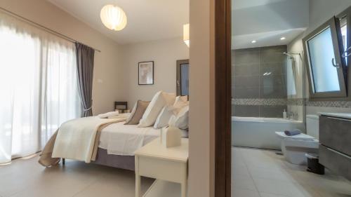 a bedroom with a bed and a bathroom with a tub at Villa Robola in Mavráta