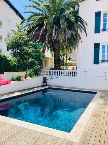 - une piscine en face d'un bâtiment avec un palmier dans l'établissement Charming 1 bedroom flat, Biarritz center with pool and car park, à Biarritz
