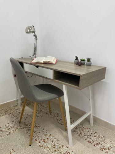 a desk with a chair with a book and a lamp at Casetta Amati in Nettuno