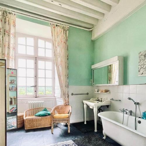 une salle de bain avec une baignoire, une chaise et une fenêtre dans l'établissement Château d'Ardenay sur merize, à Ardenay-sur-Mérize