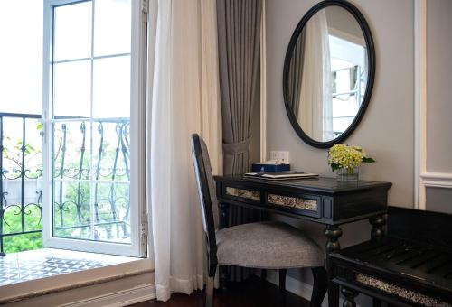 a dressing table and mirror next to a window with a desk at Acoustic Hotel & Spa in Hanoi