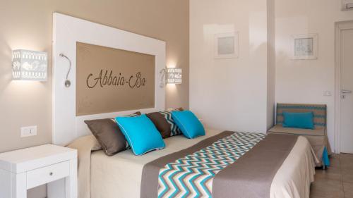 a bedroom with a large bed with blue pillows at Resort Abbaia Ba in Budoni