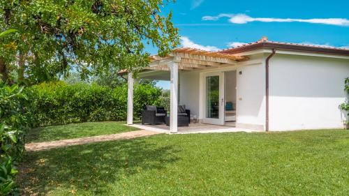 a white house with a patio in a yard at Resort Abbaia Ba in Budoni
