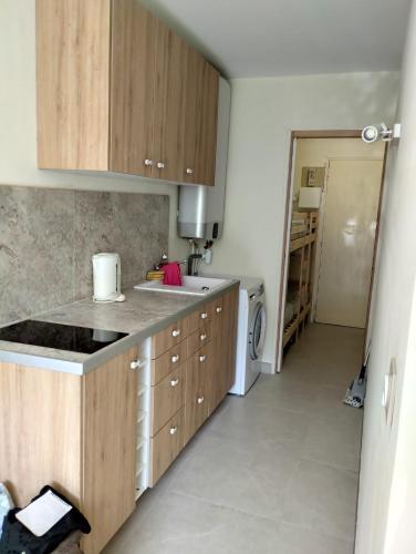 cocina con armarios de madera, lavadora y secadora en Le Regina Studio 5p mer parking, en Le Grau-du-Roi