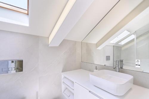 a white bathroom with a sink and a skylight at Ao Pé da Sé next to Braga Cathedral By Sé Apartamentos in Braga