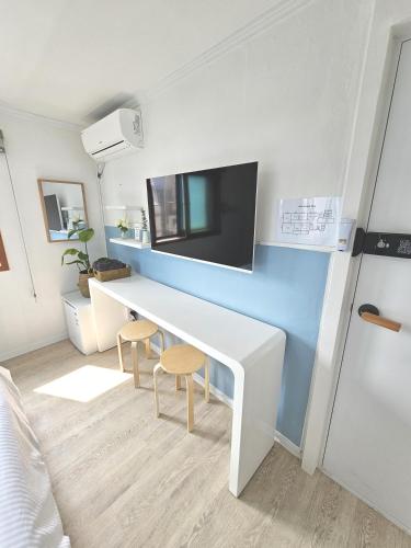 a room with a white desk and a tv on a wall at OMG house in Seoul
