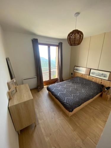 une chambre avec un lit et une grande fenêtre dans l'établissement Grande Maison Vue Montagne au calme, à Rimplas