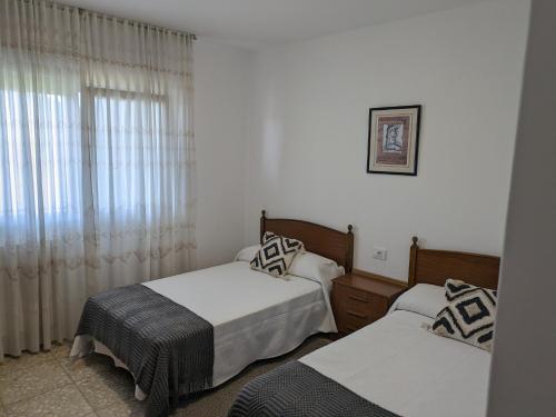 a bedroom with two beds and a window at apartamento Sol in O Grove